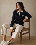 Woman seated in the navy Gammon Stamford Sporting Shirt with structured white collar and button cuffs in a warm neutral studio setting